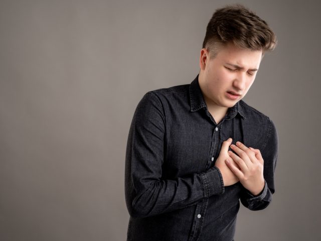 Portrait of serious stylish attractive man dressed with a casual black shirt has cardiac problem