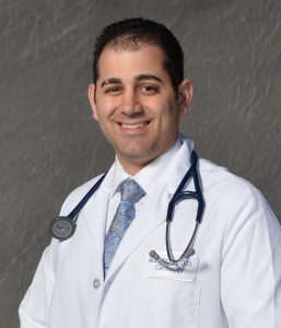 dark-haired man in white lab coat with stethoscope around his neck
