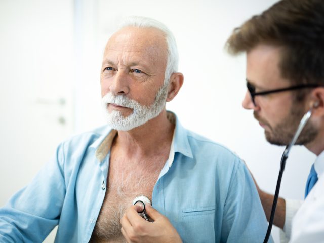 Senior man having his heart examined with stethoscope in hospital.