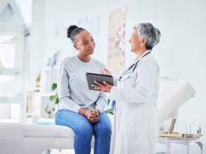 female doctor holding a tablet and talking to a patient