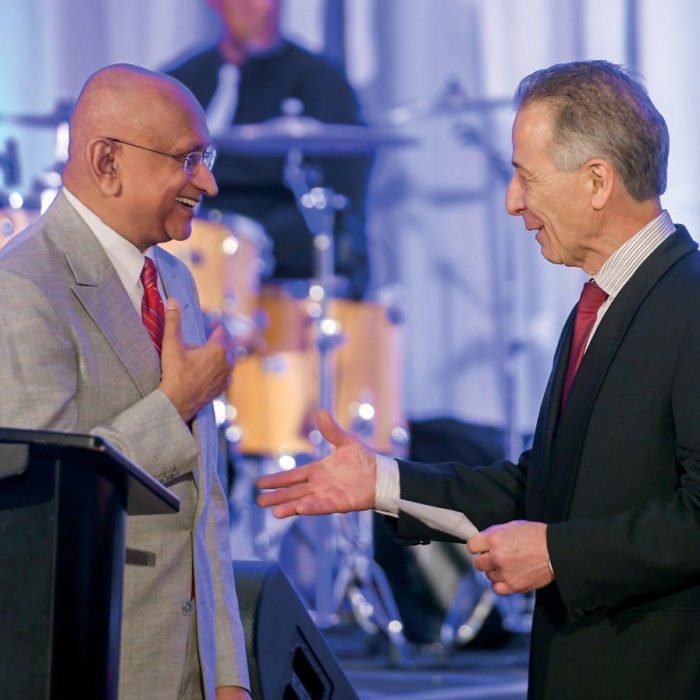 two men shaking hands while one presents the other with an award