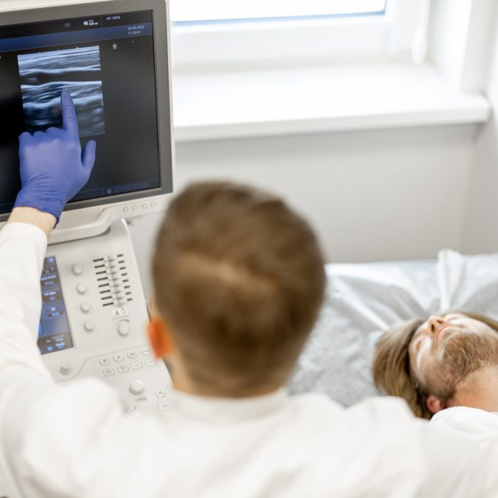 Young guy during an ultrasound diagnosis of the carotid artery. Concept of ultrasound diagnostics and men's health. Idea of examination of cardiovascular diseases