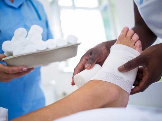 Doctor bandaging patients leg in hospital