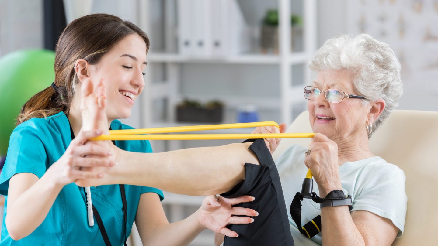 Physical therapist helps patient use resistance band