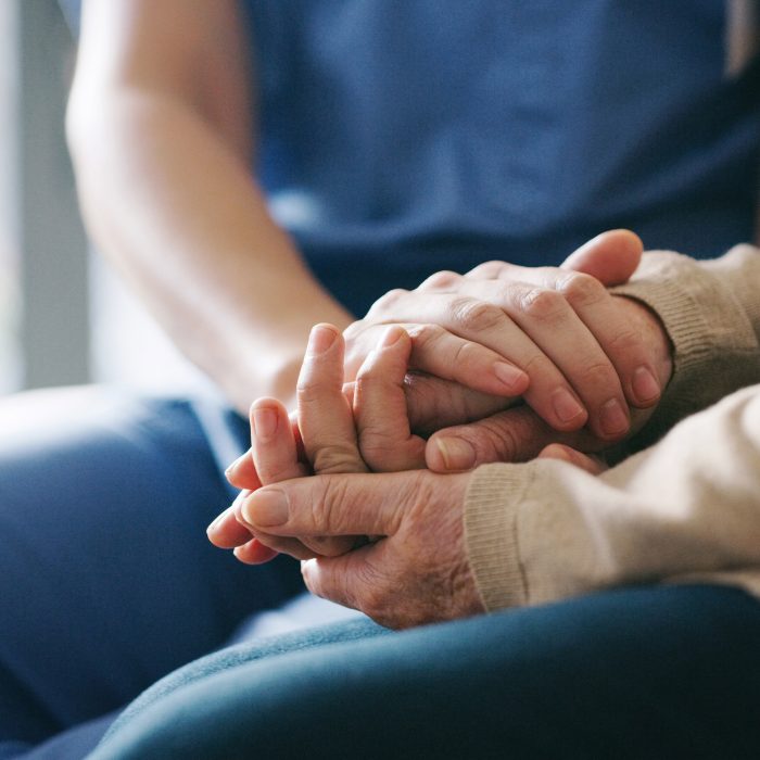 senior woman holding hands with a nurse