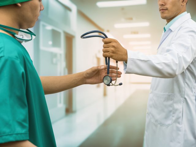 Doctor giving stethoscope to surgeon