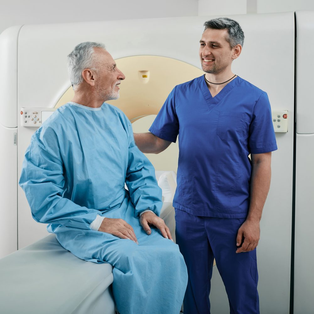 Radiographer talking with male patient in hospital radiology department prior to CT scan being performed. Computed Tomography