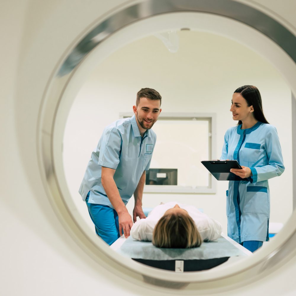 Professional Doctor Radiologist In Medical Laboratory Controls magnetic resonance imaging or computed tomography or PET Scan with Female Patient Undergoing Procedure.