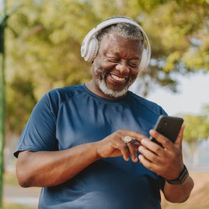 Senior man using smartphone while running in public park