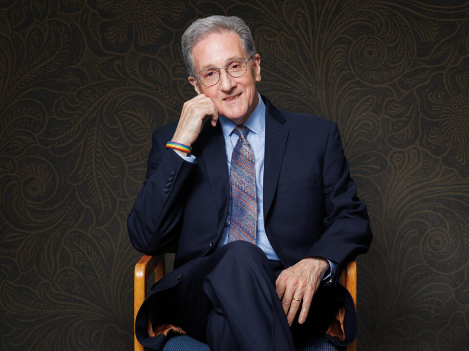 man sitting in chair with chin resting on hand