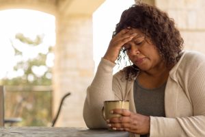 Woman looking upset staring into tea cup