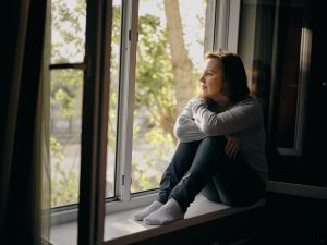 Woman sitting in window sill contemplating