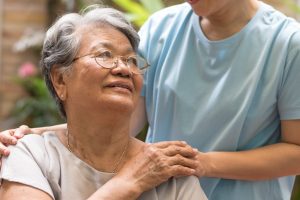 Older woman being comforted with a hand on her shoulder
