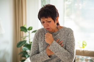 Woman holing her heart while she coughs