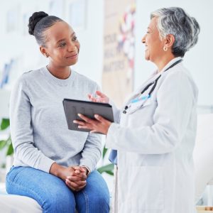 female doctor holding a tablet and talking to a patient