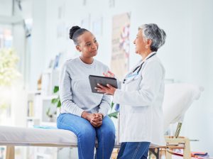 female doctor holding a tablet and talking to a patient