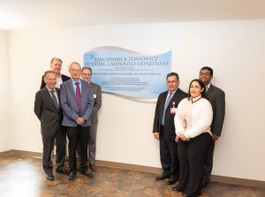 group of 7 people standing in front of plaque