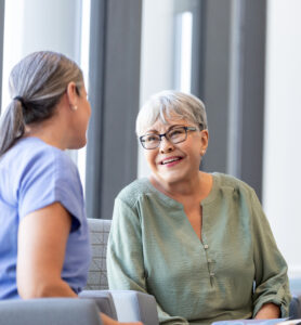 After hearing the results of her biopsy, the senior adult woman smiles while talking to her doctor.