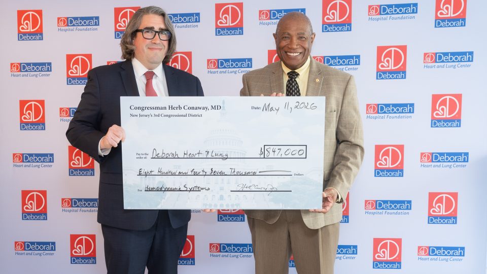 two men stand by side holding large check for $847,000